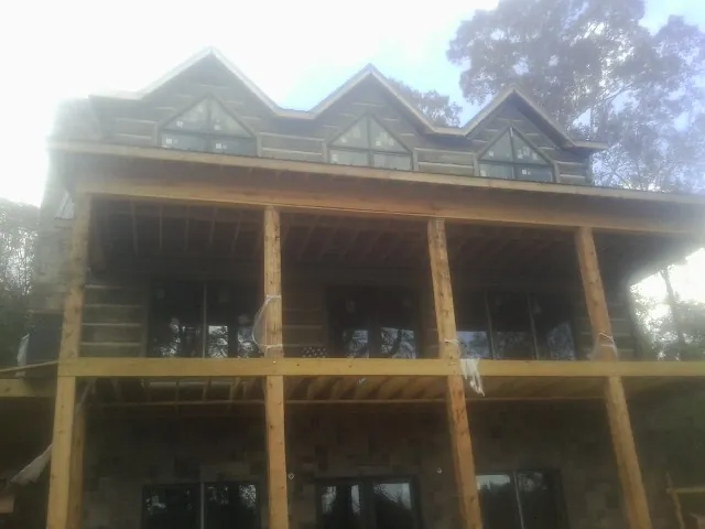 Dormers and porch framing on a large log home under construction — Roof Coating work by our crew in Smithville